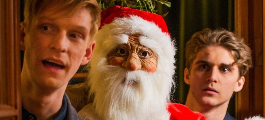 Drei Männer schauen erstaunt bis entgeistert durch eine Türöffnung in den dahinter liegenden Raum. Links und rechts die beiden jungen Hauptdarsteller des Films "Eine schöne Bescherung", zwischen ihnen ein Weihnachtsmann.